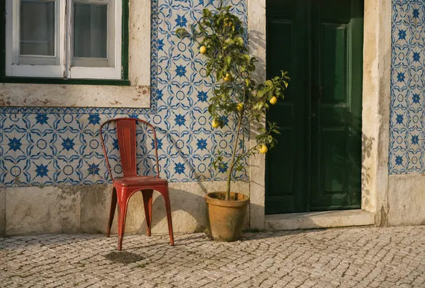 A red chair and lemon tree beside a tiled Lisbon facade